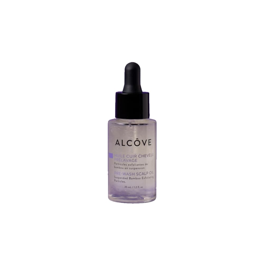A clear glass bottle with a dropper containing a scalp oil pre-wash, labeled 'ALCOVE'.