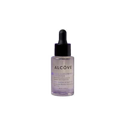 A clear glass bottle with a dropper containing a scalp oil pre-wash, labeled 'ALCOVE'.