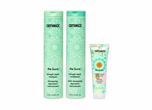A three-piece Amika 'The Kure' hair care set on a plain white background, featuring a tall mint green shampoo bottle, a matching conditioner bottle, and a smaller tube of repair cream.